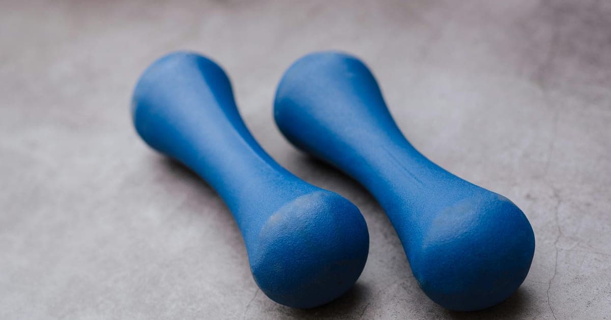 Person performing resistance training with light equipment at home, illustrating ACSM guidelines that any load builds muscle when effort is sufficient