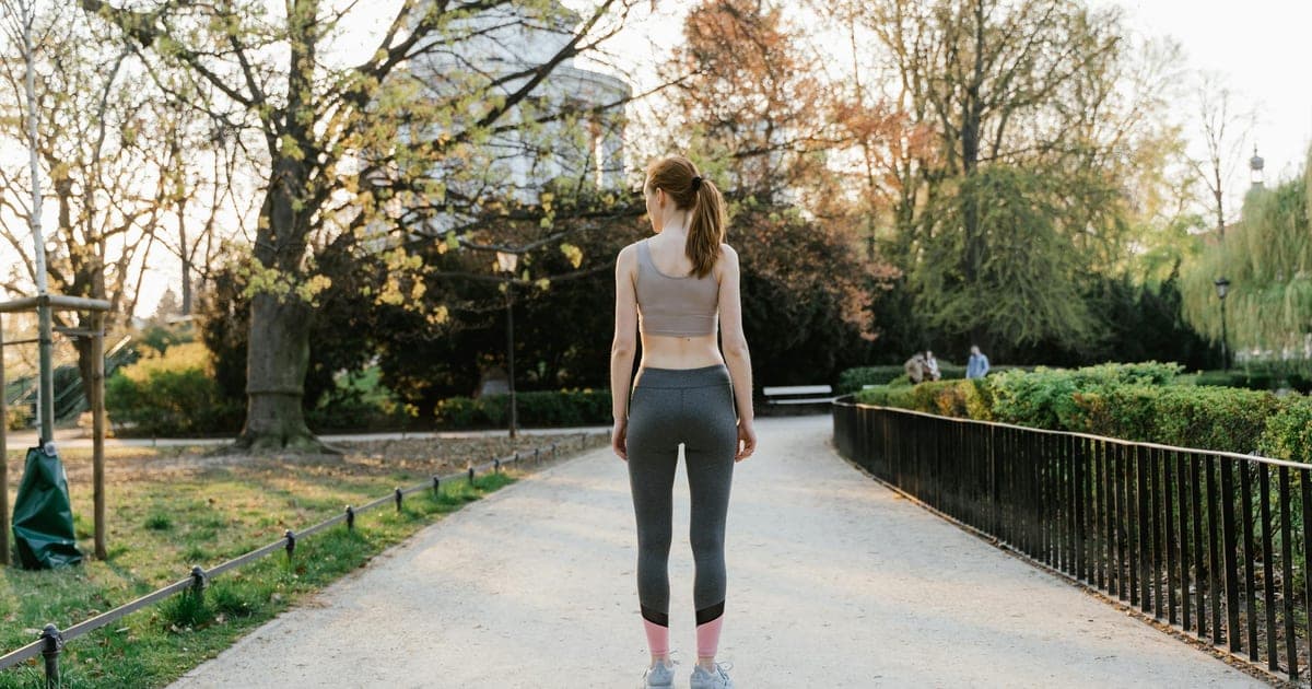Person walking outdoors in athletic clothes on a rest day, embodying light active recovery
