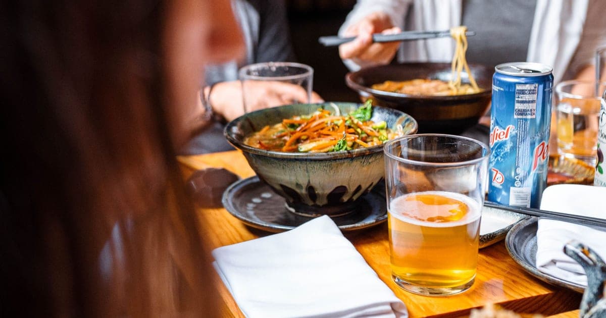 Beer glasses on a restaurant table next to a meal, illustrating the alcohol and training recovery question