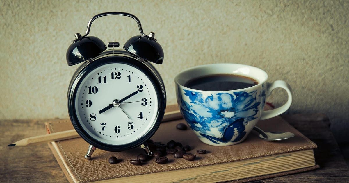 Coffee cup next to an evening clock, illustrating the decision between caffeine for evening training and protecting sleep quality