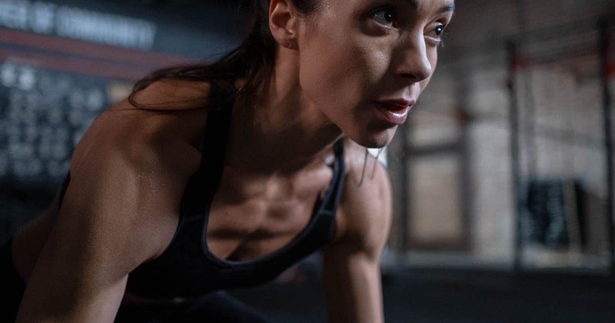 Athlete sweating during training with gym clock visible, illustrating cortisol exercise timing concerns