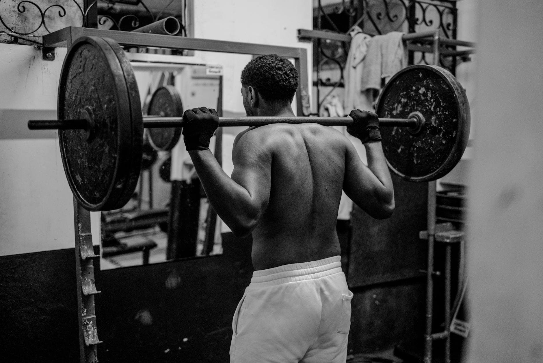 Close-up of someone gripping a barbell with a medication pen visible on a gym bench in the background