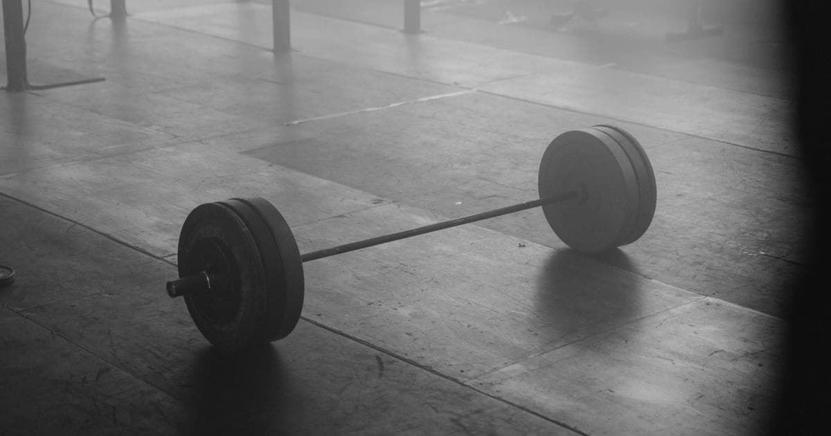 Minimalist gym setup with barbell and bench, illustrating the minimum effective dose approach to strength training
