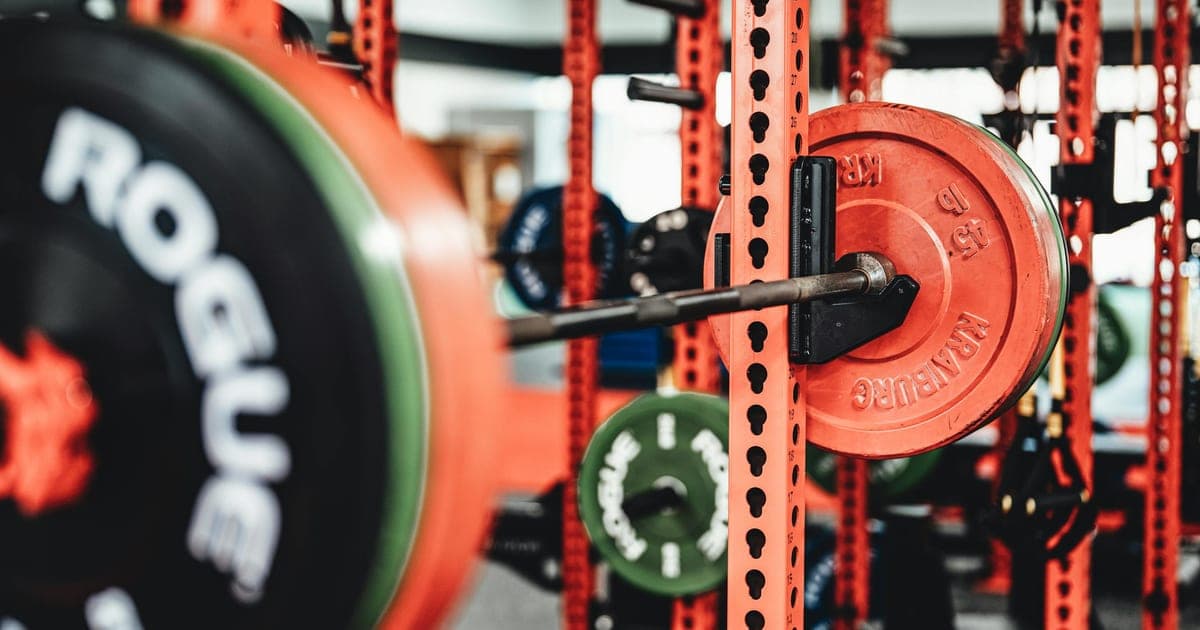Barbell resting on squat rack safety pins after a deliberately stopped set, illustrating reps in reserve training