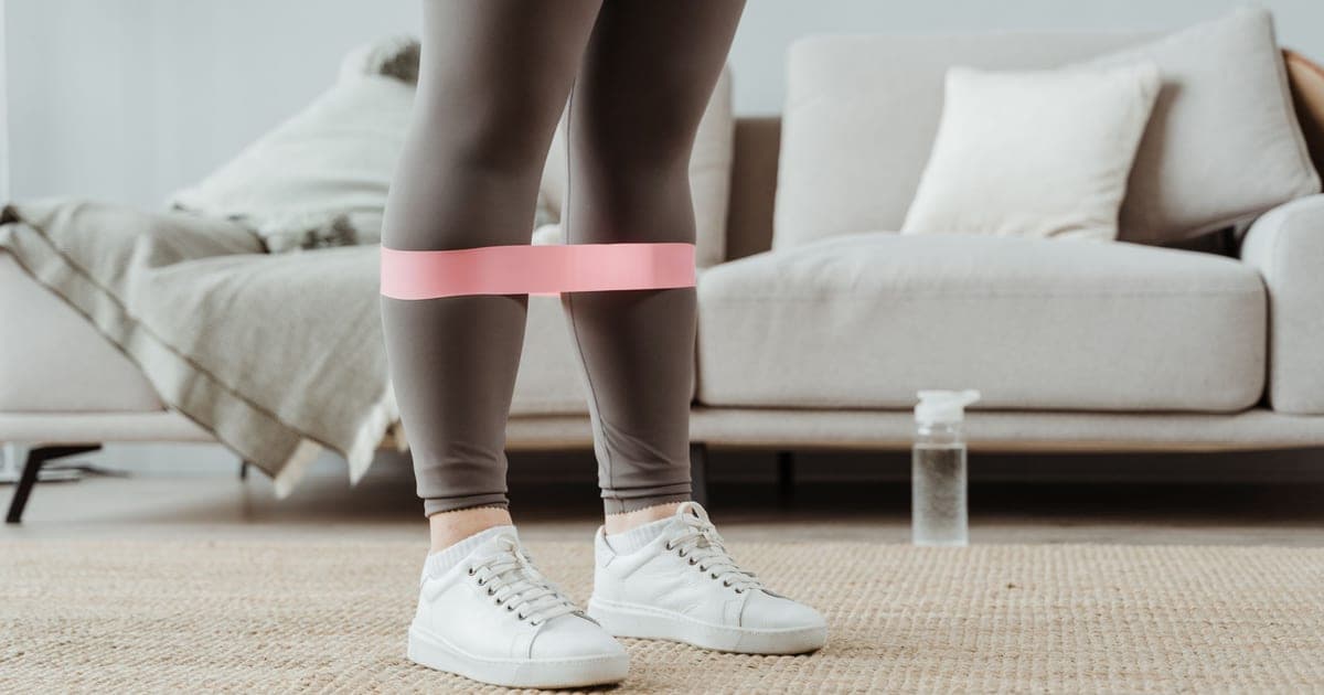 Resistance band anchored to a hotel room door with an open suitcase on the floor, illustrating training away from a gym