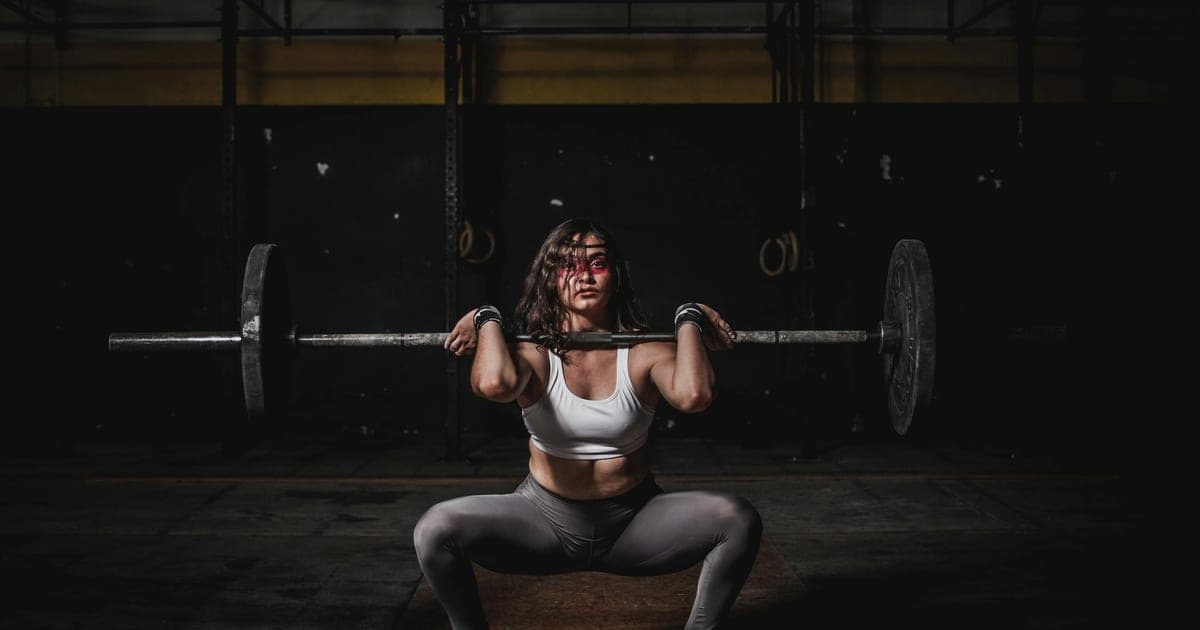 Person performing a barbell squat with visible effort, illustrating resistance training to preserve lean mass during weight loss
