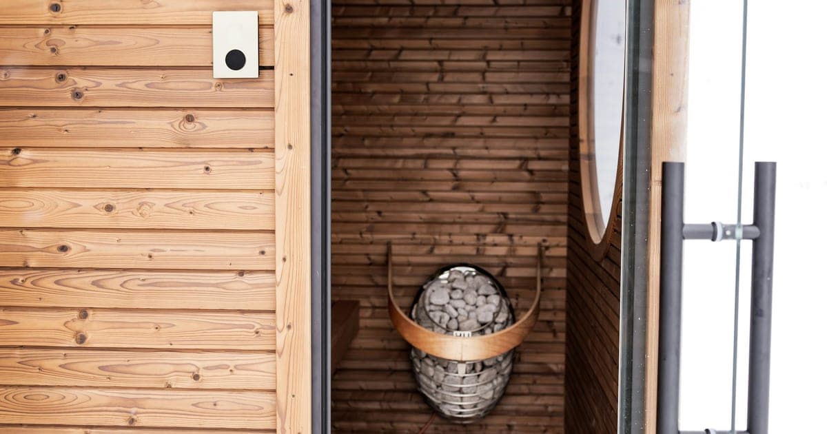 Wooden sauna interior with warm amber lighting and a towel draped over the bench after a gym session