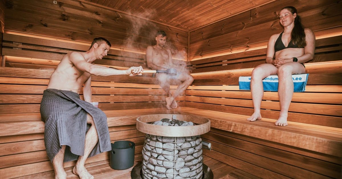 Wooden sauna door beside a cold plunge tub in a gym recovery room, illustrating the sauna vs cold plunge choice after lifting