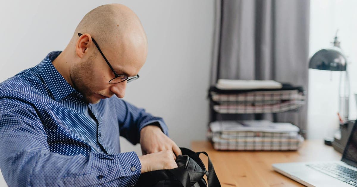 Professional checking phone calendar while holding a gym bag, showing the conflict between a packed schedule and training
